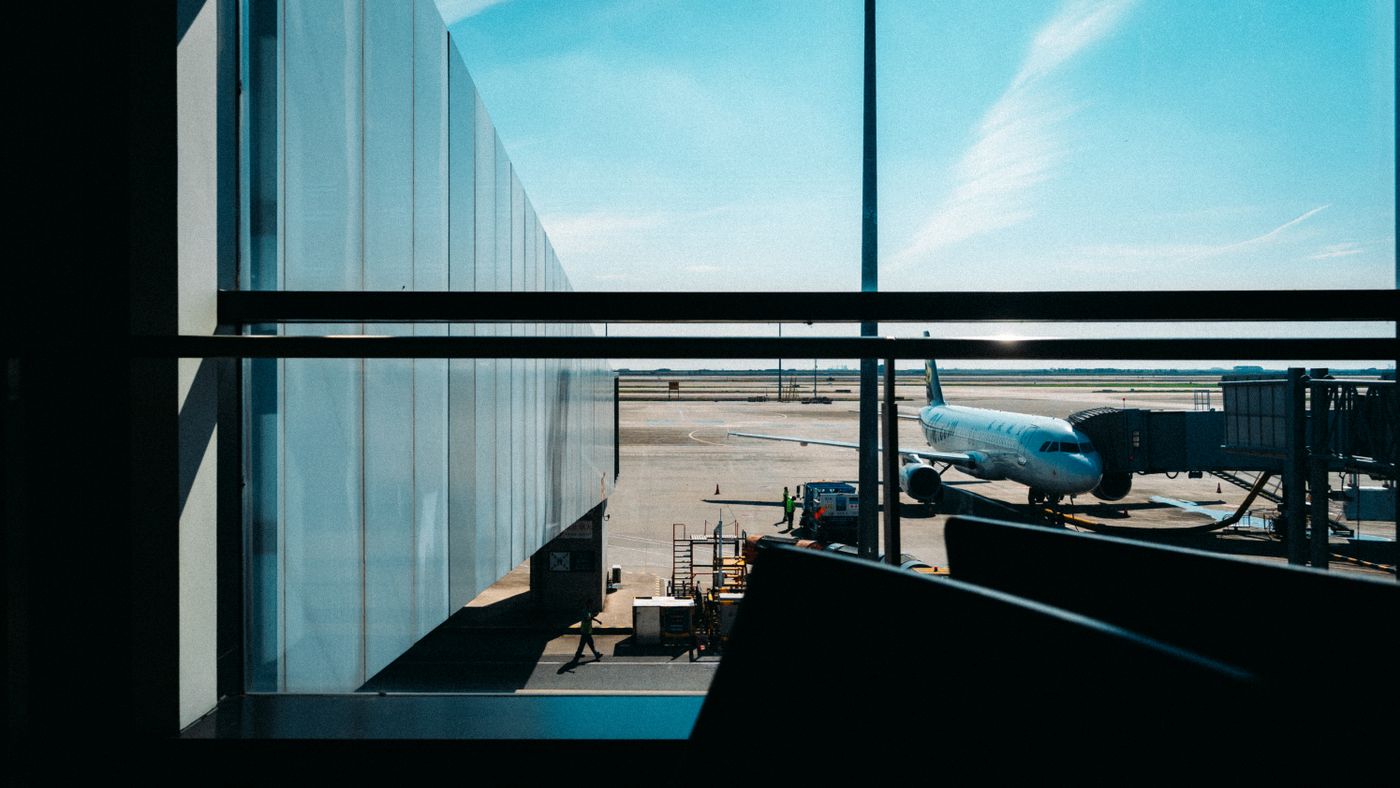 View from an airport terminal window of a plane docked at the gate under a clear blue sky